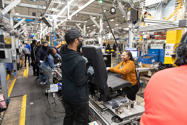 People working on seats on an assembly line in a manufacturing facility