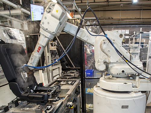 Robot and a vehicle bucket seat in a manufacturing facility