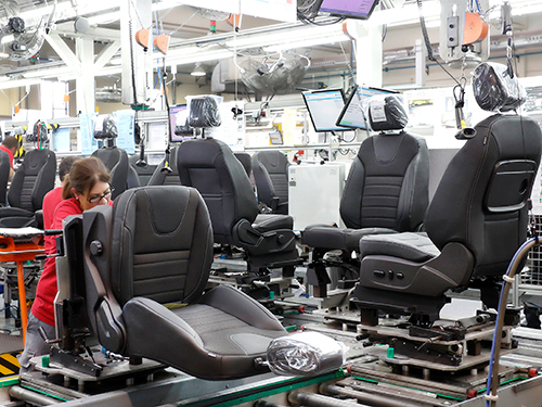 Person working on a vehicle bucket seat in a manufacturing facility