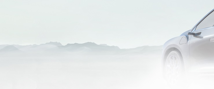 Front driver side of grey vehicle with fog and mountain range in background