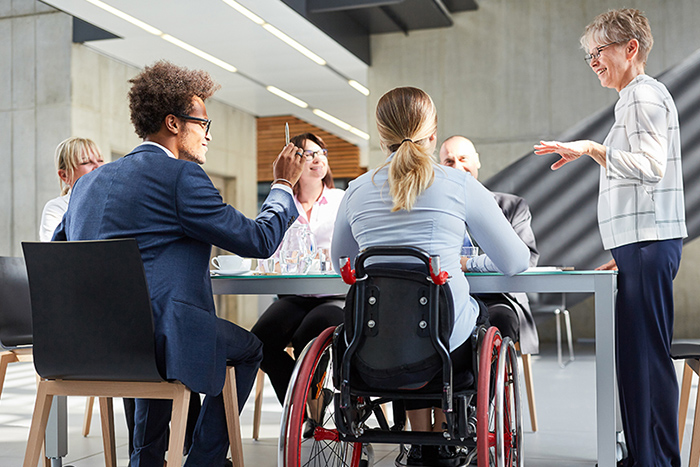 Diverse group in a meeting, including a woman in a wheelchair