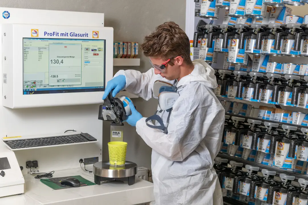 Technician in protective gear mixing paint in a laboratory