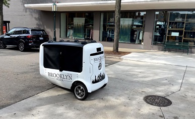 Two people standing in front of a building with electric two-wheelers.