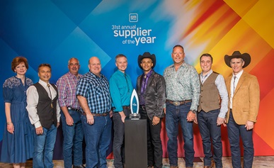 Group of people standing in front of the 2022 General Motors Supplier of the Year award