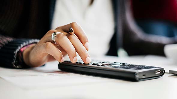 A woman typing on a pocket calculator