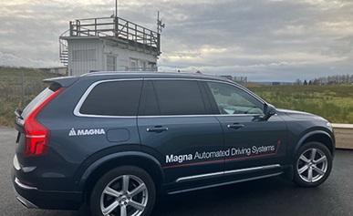 Vehicle parked on a road with a building and open field in the background