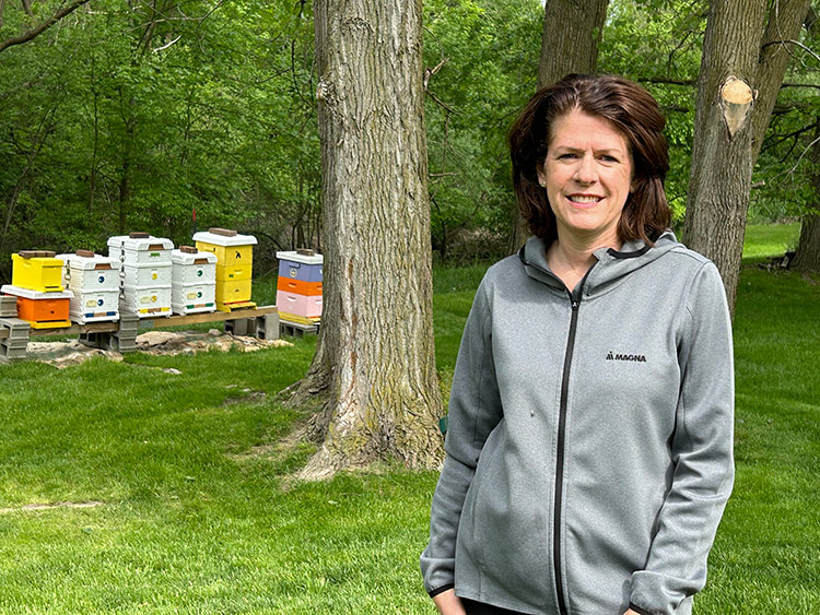 Rhiannon LaForest standing in her backyard with Bee Hives in the background