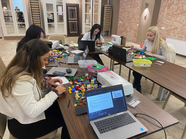 Group of people sitting at a table working with LEGO®